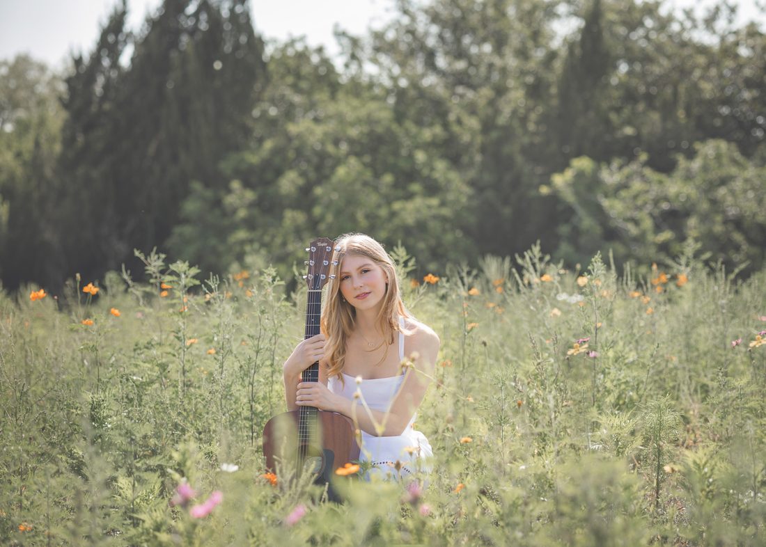 Personal branding portrait with a guitar in a wildflower field