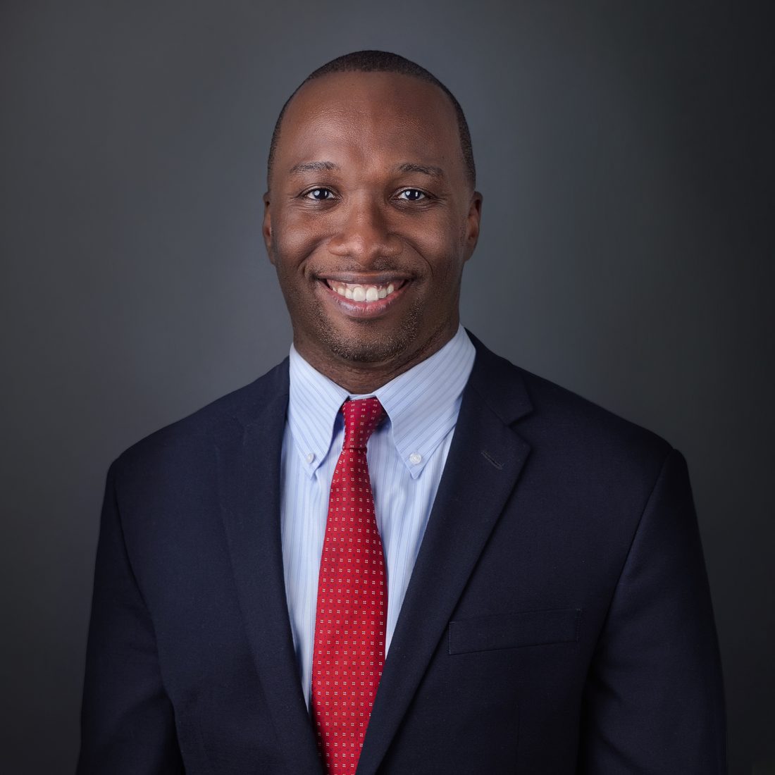 Business headshot of a man in a navy suit
