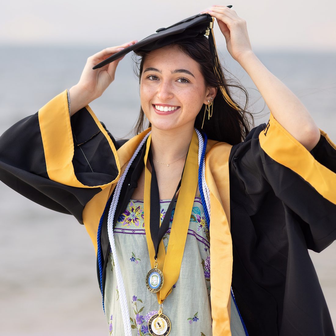 Senior portrait in cap and gown with honor medals