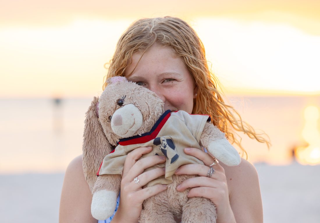 Senior portrait hugging a childhood teddy bear at the beach