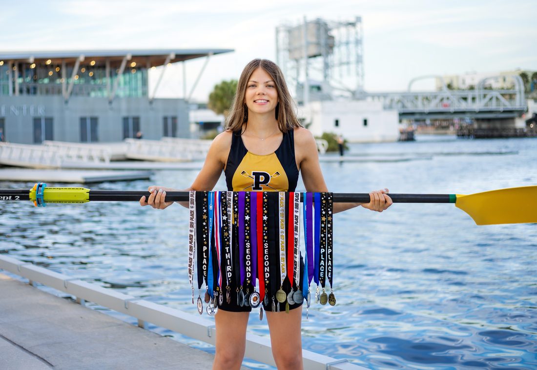 Senior portrait with rowing medals and an oar