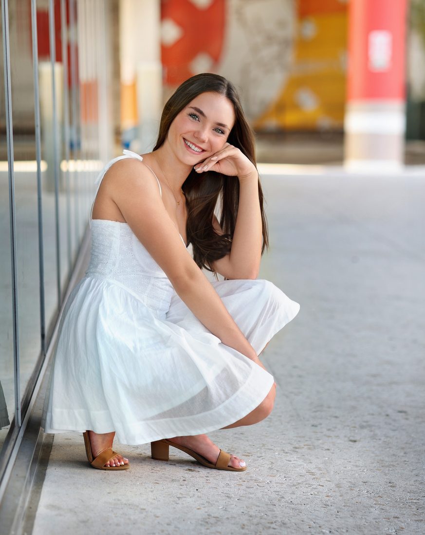 Senior portrait crouched in a white dress